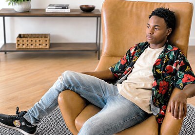 Teen boy sitting back in chair lost in thought