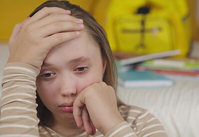 Teen girl looking anxious and overwhelmed with her hand on her head