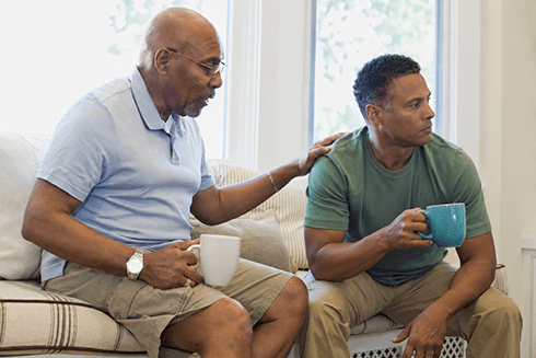 Older father sitting next to adult son giving him unsolicited advice