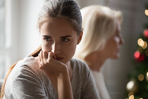 Young woman looking away from her mother with chin in palm looking frustrated