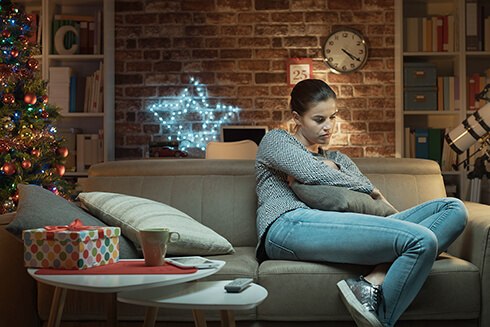 Lonely woman sitting on couch with arms crossed looking down