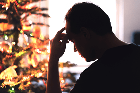 Man sitting with hand to forehead thinking about the holidays