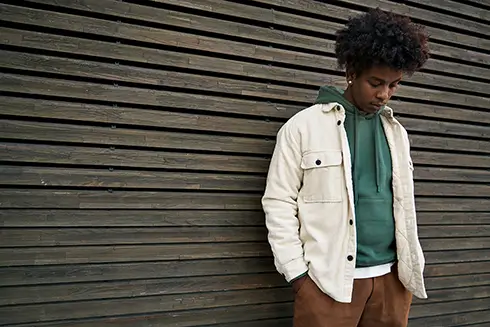 Teen boy standing alone outside looking down