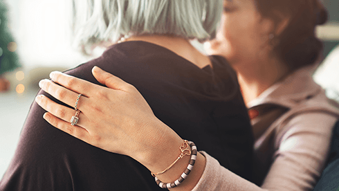 Two women comforting each other with one arm around the other ones upper back